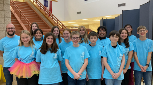 Group of people posing for a picture in front of a school building.